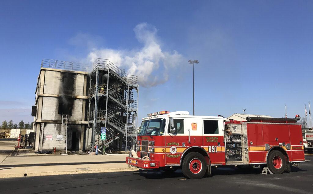 Fire truck in front of smoke-filled training structure